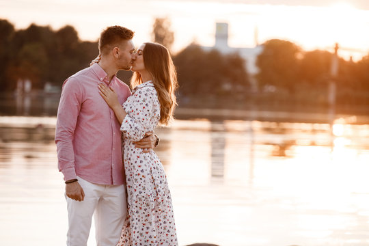 loving couple kissing on the lake at sunset. Beautiful young couple in love walking on the shore of the lake at sunset in the rays of bright light. copy space