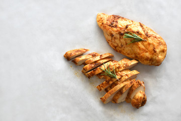 Grilled chicken breast with rosemary on a parchment paper with copy space on the left side. Selective focus. Top view photo. 