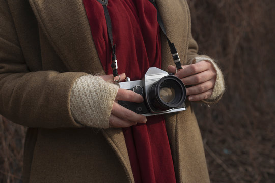 Young photographer woman is hanging an old analog camera on her neck
