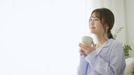 パジャマ姿でマグカップを持つ女性