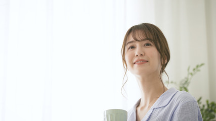 パジャマ姿でマグカップを持つ女性