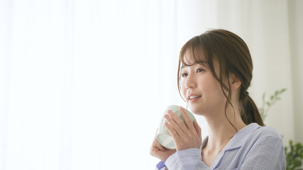 パジャマ姿でマグカップを持つ女性