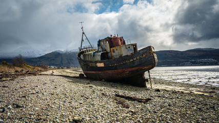 Wrecked wooden fishing boat on beach near Corpach village, Fort William, Scotland, United Kingdom....