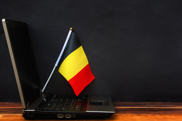  flag of Belgium , computer, laptop on table and dark background