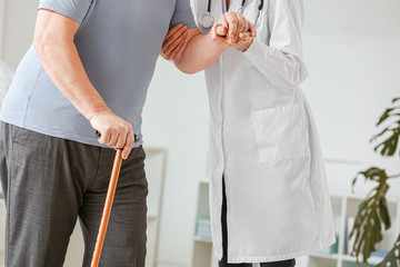 Female doctor working with senior man suffering from Parkinson syndrome in clinic