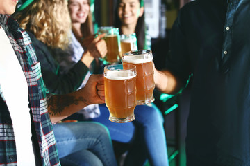 Young friends with beer celebrating St. Patrick's Day in pub, closeup