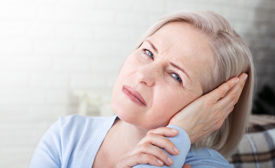 Tinnitus. Closeup up side profile sick female having ear pain touching her painful head.
