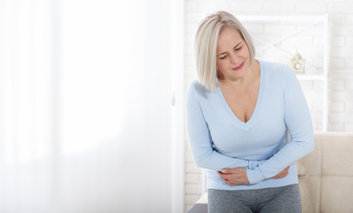 Middle aged woman suffering from abdominal pain while at home