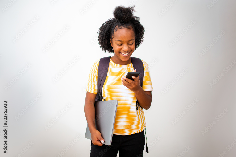 Wall mural african american teenage girl with laptop and mobile phone against white background