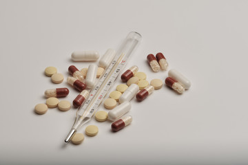 pills and thermometer on white background