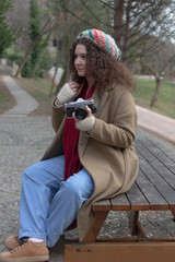 Curly haired photographer woman holding her camera in the park and shooting