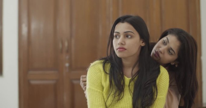 Medium shot ms of young Indian woman hugs her lost best friend in bed from behind in a sad and miserable mood to lighten up things by gently rocking and swaying slowly in India, slow-motion 60fps 