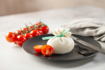 Italian cheese burrata with tomatoes on a plate with a fork