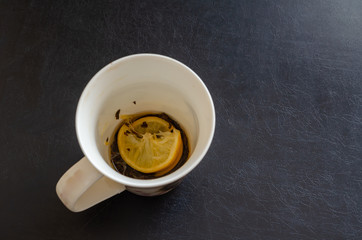 Empty cup after tea with lemon. Top view of the remaining two slices of lemon at the bottom of the...