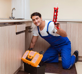 Young repairman working at the kitchen