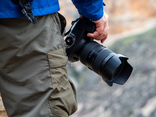 Hand of a man holding a camera in the mountain