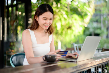 Girl buying online with credit card and a tablet sitting in the garden at home in holiday, Online Shopping Concept.