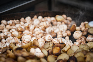 Grilling small potatoes and mushrooms. Street food. Close up of appetizing grilled potatoes and mushrooms on the bbq grill.