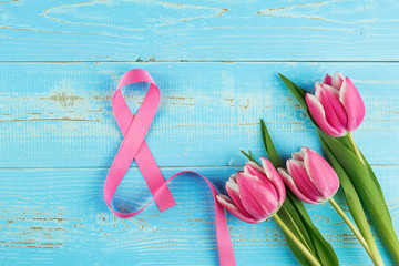 Pink tulip flower and 8th Ribbon symbol on blue wood table background with copy space for text. Love, Equal and International Women day concept