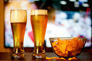 beer glasses and chips in front of tv - watching world cup football at home - soccer supporters