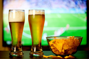 beer glasses and chips in front of tv - watching world cup football at home - soccer supporters