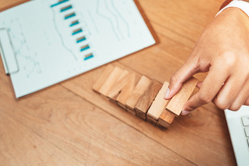 Male hand stacking wooden blocks. Business development and growth concept