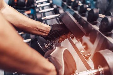 Sporty young man lifting a dumbbell in a gym. fitness, gym, workout and lifte style concept.