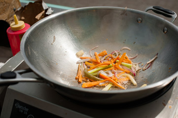 Cooking vegetables in a wok pan. Street food