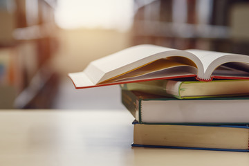 Open book on stack of books in library at school, university, college.