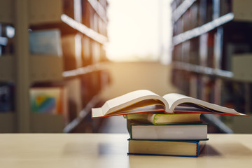 Open book on stack of books in library at school, university, college.