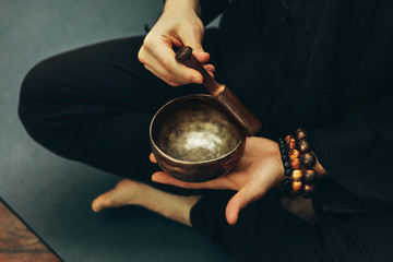 top view of a man sitting in a lotus position with a rosary on his hand playing on singing bowls. Relaxation and meditation. Alternative medicine. Tibetan and Himalayan singing bowls. Making sound.