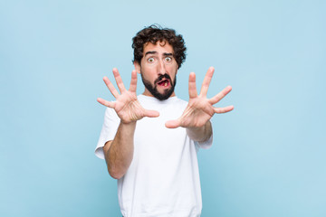young crazy bearded man feeling terrified, backing off and screaming in horror and panic, reacting...