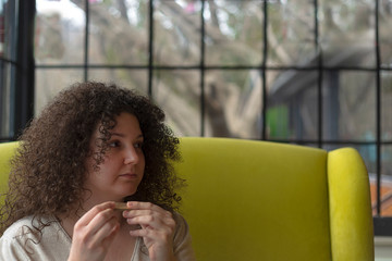 Fototapeta na wymiar Young woman with curly hair is preparing a cigarette in a cafe