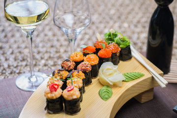 Set of several different rolls on a wooden stand on a table in a Japanese restaurant. Japanese traditional sushi and rolls.