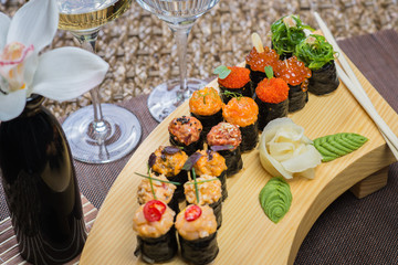 Set of several different rolls on a wooden stand on a table in a Japanese restaurant. Japanese traditional sushi and rolls.