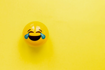 Funny yellow face very much laughs to tears on a yellow flat background. Flat-lay, top view,mockup - obrazy, fototapety, plakaty