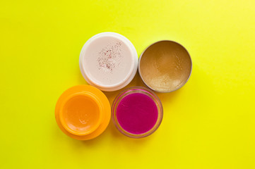 four tubes of colorful lip balms and lipsticks on a bright, clear yellow background. Ready-made layout for beauty salon and cosmetics advertising. Skin care in the cold season.