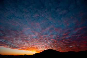 Fantastic gradient sundown cloudscape, mountain silhouette on the bottom of image