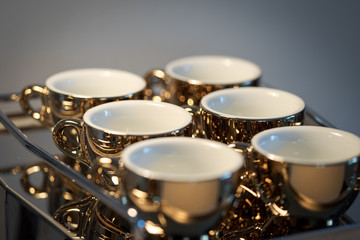 Full frame shot of six golden espresso cups standing on italian chrome-plated coffee maker