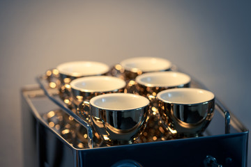 Full frame shot of six golden espresso cups standing on italian chrome-plated coffee maker