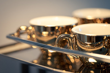 Detail of golden espresso cups standing on italian chrome-plated coffee maker