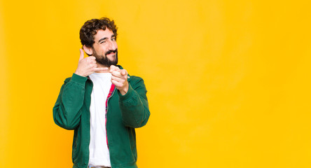 young crazy bearded man smiling cheerfully and pointing to camera while making a call you later...