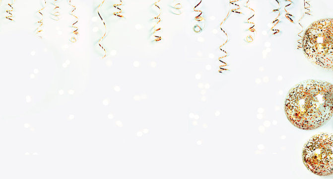 Gold serpentine and balloons with colorful confetti on shiny bokeh lights on festive background, banner. Holiday decoration for parties, birthday, greeting card with copy space