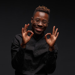 Emotional portrait of a young African man in black clothing against a dark background. Studio photography.