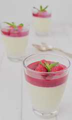 Italian dessert Panna cotta with white chocolate and raspberry sauce, fresh berries and mint.