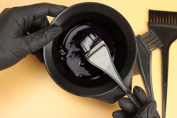 Girl in black gloves mixes hair dye in a bowl