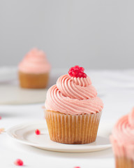 Cupcake with pink buttercream and pomegranate seeds