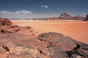 Fototapeta premium Panoramiczny widok na góry skaliste i czerwony piasek na jordańskiej pustyni Wadi Rum.