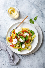 Italian pasta mafalde with green peas, prosciutto, burrata,  and spinach and glass of white wine