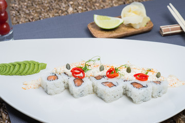 Traditional rolls with fish and rice on a white plate with sauce and wasabi. Japanese food.